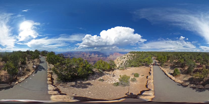 Paved Trail of Time beside layered Grand Canyon views beneath storm clouds