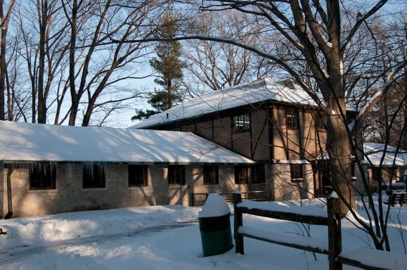 Snow-covered stone exterior of the Eagle Creek Park Ornithology Center among mature trees