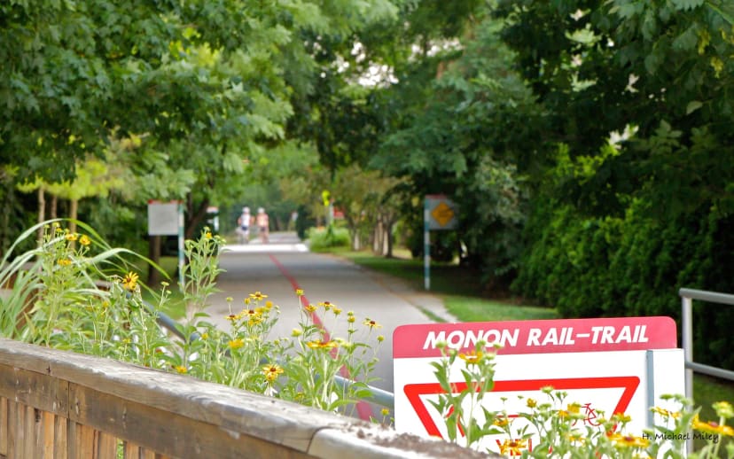 Monon Rail-Trail sign beside the paved, tree-lined trail in Indianapolis