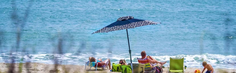 Visitors under a Shibumi-style shade at Fort Macon beach