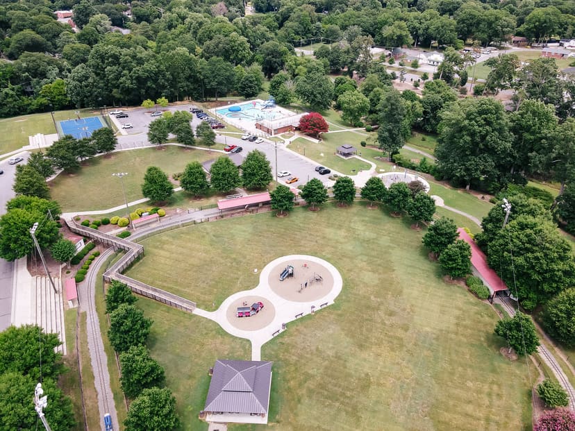 Aerial overview of Lineberger Park showing the miniature train, playgrounds, pool, splash pad, courts, shelters, and walking paths