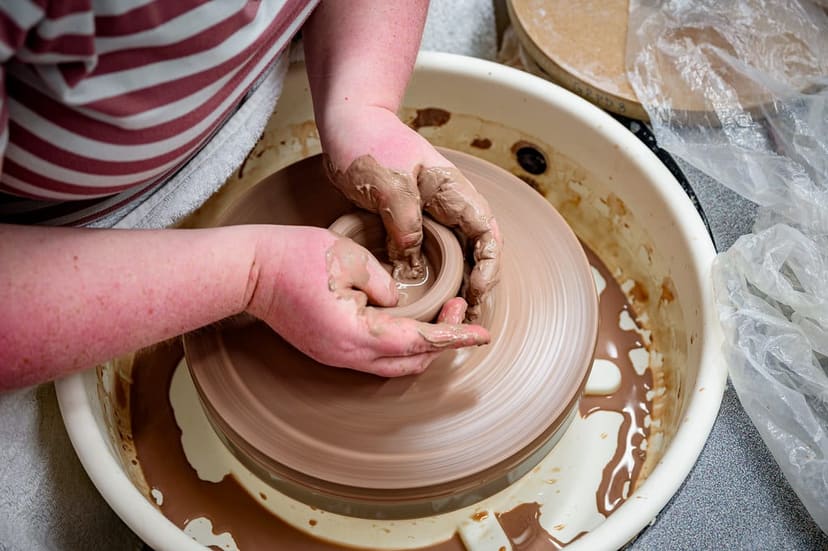 Hands shaping clay on a pottery wheel during an arts class at Jaycee Park in Greenville
