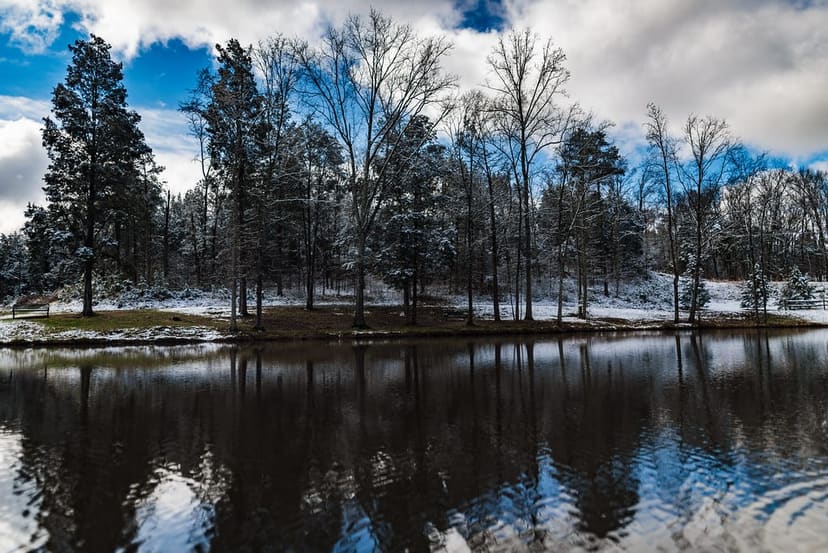 Wooded fishing pond with picnic tables after light snow at Pharr Mill Park in Harrisburg
