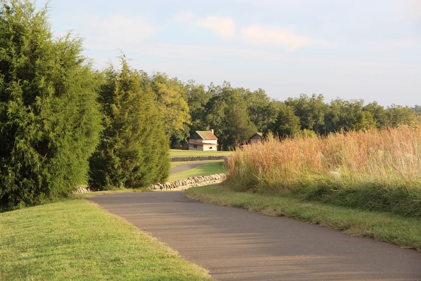 Paved walking trail descending toward the restored farm buildings at E. Carroll Joyner Park