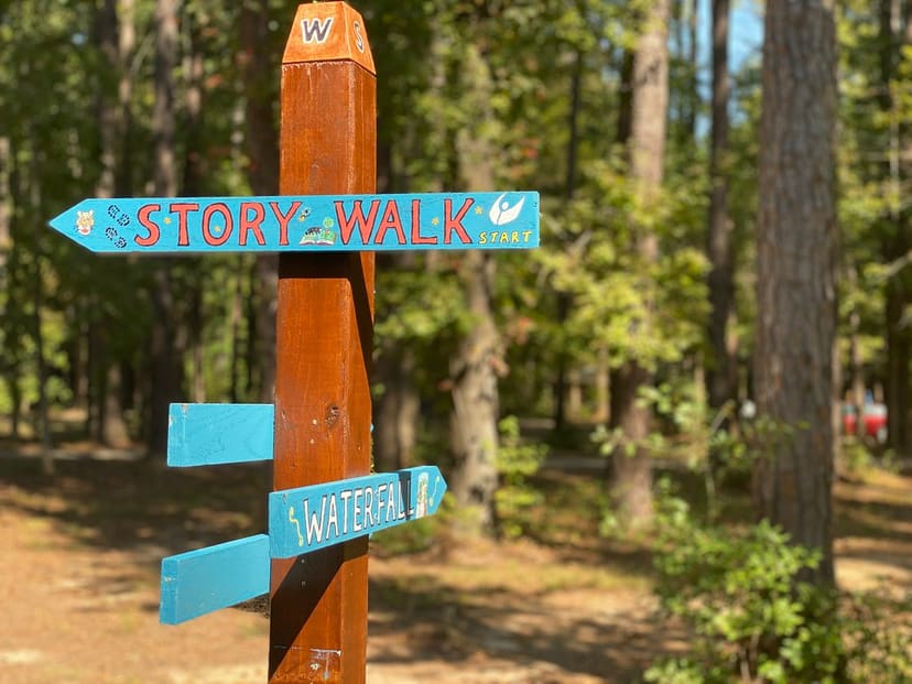Clark Park trail wayfinding sign pointing to the StoryWalk and waterfall